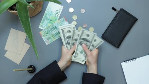 Hands Counting Money Overhead on Desk
