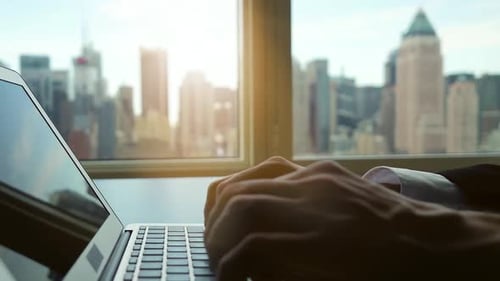 Man Typing on Laptop Overlooking City Skyline