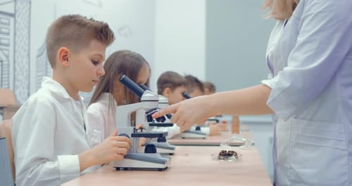 Children Using Microscopes in Science Classroom with Teacher