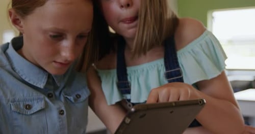 Two girls using digital tablet in the class
