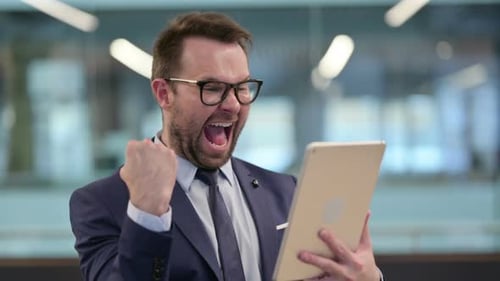 Happy Businessman Celebrating Success Using Tablet