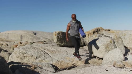 Senior african american man exercising walking on rocks by the sea