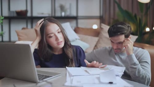 Woman and Man Discuss Papers and Laptop Indoors