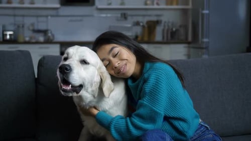 Woman Cuddling with Golden Retriever Dog on Couch