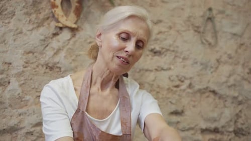 Vieille potière travaillant sur un tour de potier fabriquant un pot en argile