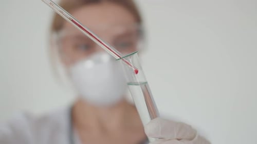Medical Researcher Drops Red Liquid into Test Tube