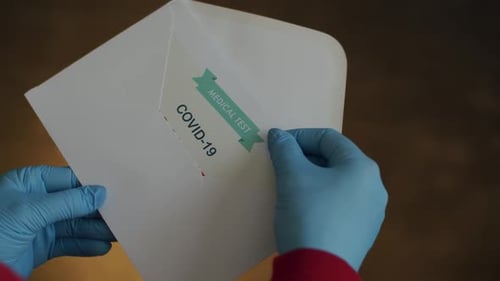 Persona que saca un certificado con resultados positivos en Covid-19 de un sobre