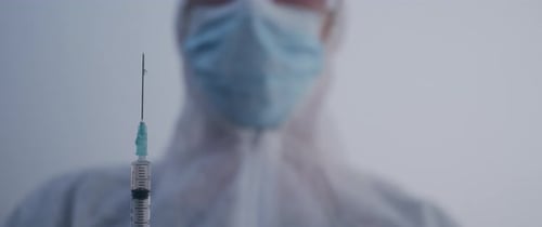 Person hält eine Spritze tropfend in Zeitlupe