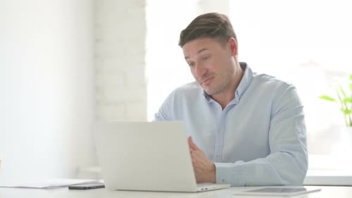 Man Talking on Video Call on Laptop in Office