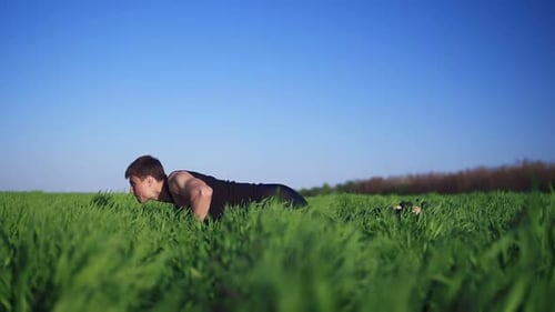Athletic Man Doing Push Ups in a Field
