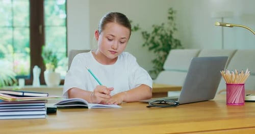 Focused Girl Studying at Desk with Laptop