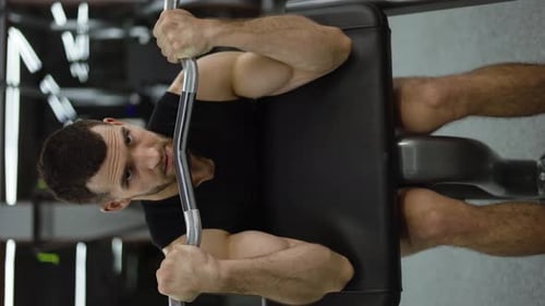 Muscular Bodybuilder Doing Weight Lifting in Gym on Chair