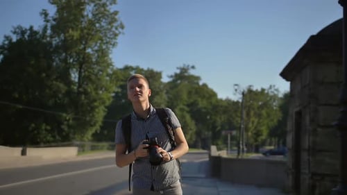 A Tourist Standing Near the Road and Looking for Good Camera Angles for Taking Great Shot