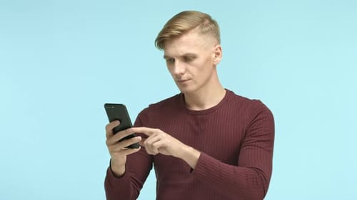 Young Man Reacts to Content on Smartphone