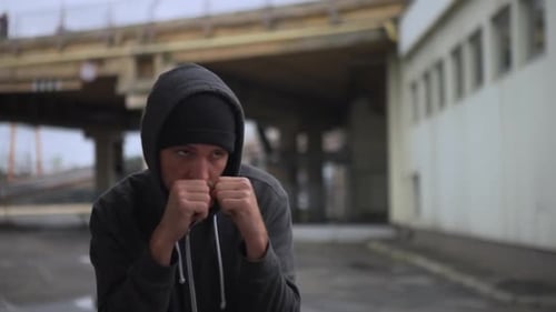 Front View Concentrated Sporty Man in Comfortable Clothes Boxing Practising on Street Under
