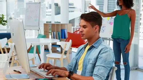Man Works at Computer, Woman Uses VR Headset