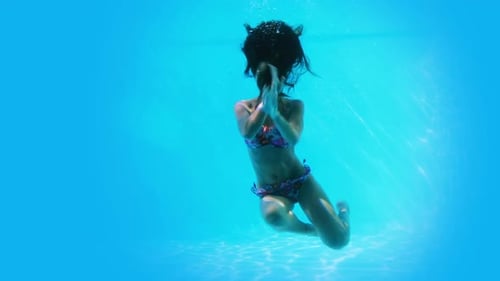 Pretty brunette swimming underwater in pool