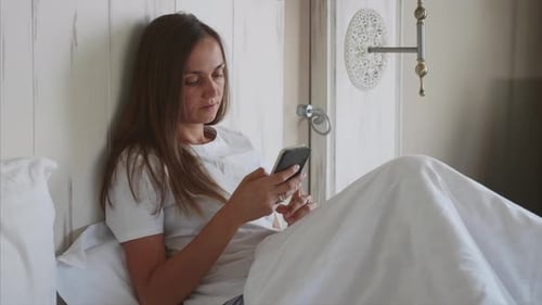 Woman Using Smartphone Relaxing in Bed
