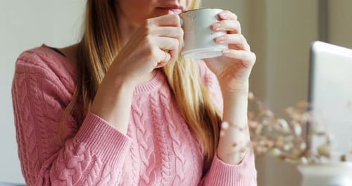 Woman Drinking from Mug Indoors at Table