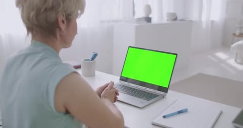 Blonde Woman Is Communicating Online By Video Call, Looking at Green Screen of Laptop for Chroma Key