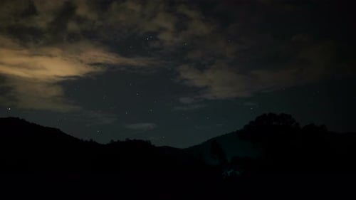 Mountains Under Night Sky with Moving Clouds