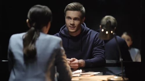 Suspect Being Interrogated by Detective in Dark Room