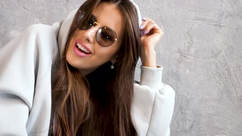 Stylish Woman Posing with Sunglasses and Hoodie