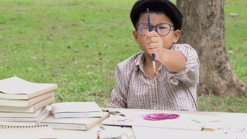 Child Paints with Brush in a Green Park