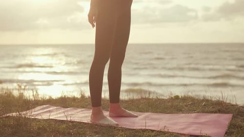 Young Woman Doing Squats at Sunrise by Ocean