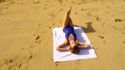 Woman Relaxes on Beach Towel in the Sunlight