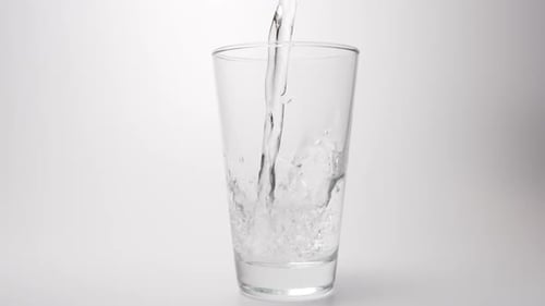 Clear water pour into a transparent glass on a white background