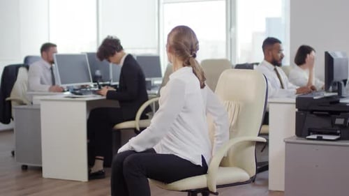 Woman Stretching at Desk in Bright Office