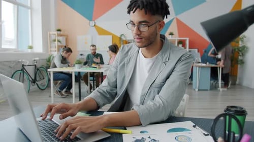 Happy Afro-American Guy Using Laptop Typing and Smiling Enjoying Business Communication in Office