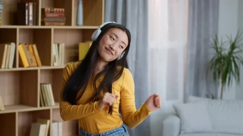 Enthusiastic Woman Dances in Living Room with Headphones