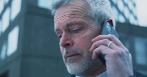 Caucasian man with blue eyes and white hair speaking on the phone