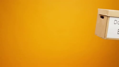 Arms Hold a Donation Box on Yellow Background