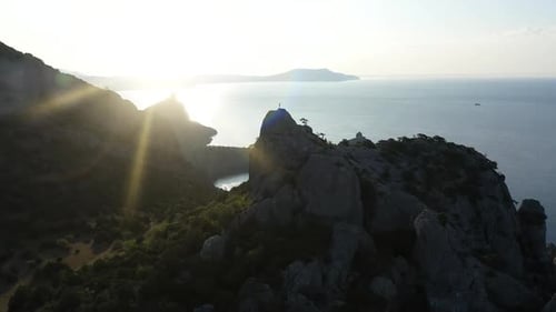Aerial Silhouette of Young Woman Raising Her Hands Standing on the Top of a Mountain Over the Sea at