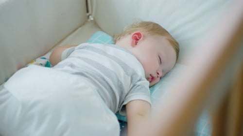Infant Sleeps Peacefully in a White Crib