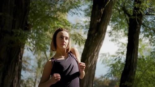 Woman Stretches Arms in Sunny Urban Park