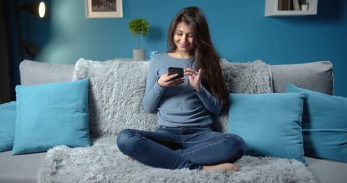 Woman Using Mobile Phone While Sitting on Couch