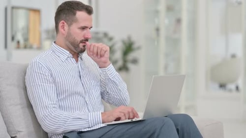 Adult Man Working on Laptop While Coughing