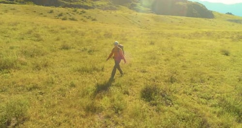 Flight Over Backpack Hiking Tourist Walking Across Green Mountain Field, Huge Rural Valley at Summer