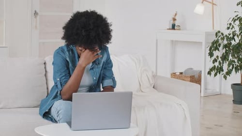 Woman on Couch Looks Stressed While Using Laptop