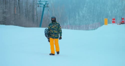 Snowboarder Walking on Snowy Mountain in Winter