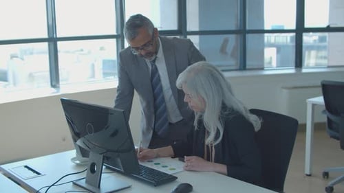 Focused Male Boss and Female Manager Discussing Reports