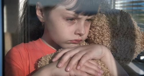 Child Hugs Teddy Bear Looking out Window