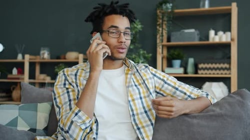 Fröhliche afroamerikanische Studentin telefoniert zu Hause drinnen