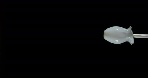 Milch explodiert und spritzt auf schwarzem Hintergrund, Zeitlupe 4K
