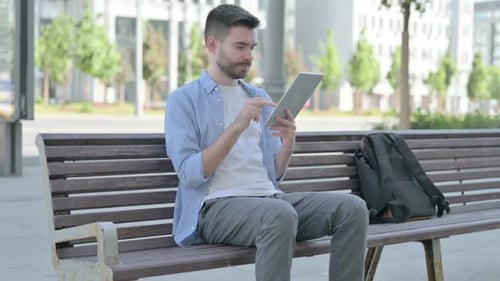 Man Using Tablet on City Park Bench