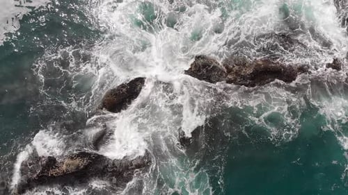 Luftaufnahme von oben von Drohne of Ocean Blue Waves Break auf einer hohen Klippe eines felsigen Berges